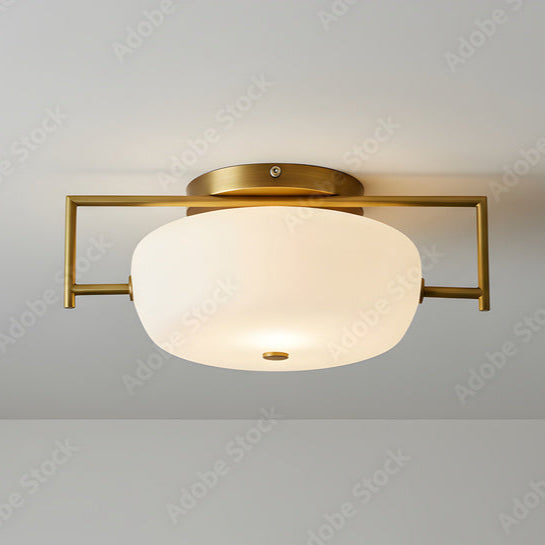 Ceiling light fixture with gold frame and white glass shade on a plain ceiling.